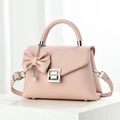 Light pink pebbled leather handbag with silver G buckle and pearl bow charm on white stand - Pink