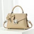 Close-up of beige pebble leather handbag with silver clasp and pearl bow charm - Khaki