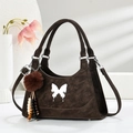 Sac à main marron mat avec papillon argenté et pompon sur support géométrique blanc - Café
