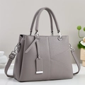 Close-up of gray pebble leather tote with asymmetric geometric stitching and silver hardware - Gray