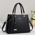 Détail de la texture grainée noire et des ferrures argentées du sac à main chic - Noir
