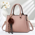 Detail of pink shoulder bag featuring herringbone texture, gold rings, and decorative fur charm - Pink