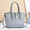 Detail of light blue crossbody bag featuring woven texture and gold hardware clasp - Blue