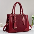 Detail of burgundy faux leather handbag with woven texture and gold hardware accents - Red