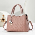 Detalle de textura de cuero acolchado y colgante náutico en el bolso rosa elegante - Rosa