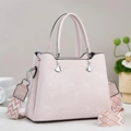 Minimalistische Handtasche in Hellrosa mit gewebtem Gurt und Metallanhängern - Rosa