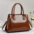 Detail of glossy brown crocodile pattern patent leather handbag with adjustable strap - Earthy Yellow