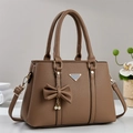 Detalle de bolso en cuero marrón con textura de lichi, colgante de perla y herrajes - Caqui
