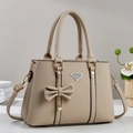 Detalle de bolso beige con textura de lichi, colgante de lazo y adornos metálicos - Albaricoque