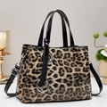 Close-up of glossy leopard print handbag with silver ring hardware and strap detail - Khaki