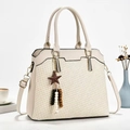 Chic cream woven handbag with star charm and shoulder strap in an elegant lifestyle setting - Off-white