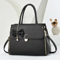 Elegante bolso negro con textura litchi, herrajes dorados y colgante de lazo y perla - Negro
