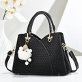 Elegante schwarze gewebte Handtasche mit Goldbeschlägen und Plüsch-Anhänger auf Weiß - Schwarz