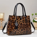 Dettaglio della borsa leopardata con manici neri lucidi e hardware metallico a V - Giallo Terra