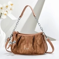 Close-up of caramel pleated handbag with silver chain and sphere charms on white podium - Earthy Yellow