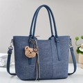 Blue woven tote bag with leather handles and a brown plush bear charm accessory - Blue