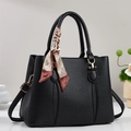Close-up of black lychee leather tote bag with silk scarf on handle and gold hardware - Black