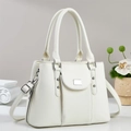 White lychee pattern handbag with dual handles and long shoulder strap in minimalist setting - White