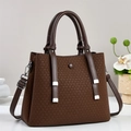 Détail de la texture tressée marron foncé sur sac à main femme avec ferrures argentées - café