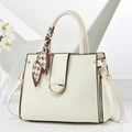 Dettaglio borsa crema con chiusura dorata e manico decorato con foulard di seta elegante - Bianco