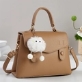 Detail der kamelfarbenen Lederhandtasche mit Lychee-Narbe und Plüschmonster-Anhänger - Khaki