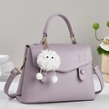 Nahaufnahme der lila Handtasche mit Litschi-Muster und einem süßen weißen Plüsch-Anhänger - Lila