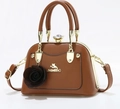 Detail of brown leather shell handbag featuring golden cat logo and rose flower pendant - Brown