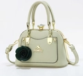 Detail of light green satchel with gold cat logo and dark green rose floral charm - Cyan