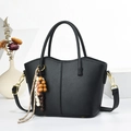 Dettaglio borsa in pelle martellata nera con finiture dorate e pendente a nappa - Nero