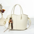 Dettaglio borsa a secchiello in pelle bianca con ciondolo in legno e hardware oro - Bianco Sporco