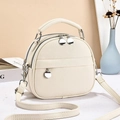 Detailed view of cream leather shell bag featuring litchi grain and silver hardware - White