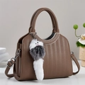 Detailed view of a brown textured bucket bag with a plush charm and adjustable strap - Coffee