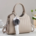 Dettaglio borsa a secchiello beige con trama a nido d'ape e ciondolo di peluche - Albicocca