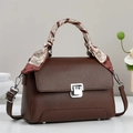 Détail du sac à main en cuir marron avec fermoir argenté et poignée en foulard de soie - café