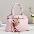 Detailed close-up of pink litchi grain leather handbag with cute bear charm and twist lock - Pink