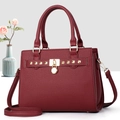 Detail of burgundy pebbled leather handbag with gold hardware and square studs - Burgundy