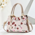 Detail of elegant handbag with cherry print, golden metal hardware and heart pendant - Khaki