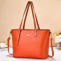 Close-up of orange faux leather tote bag featuring gold hardware and adjustable strap - Red