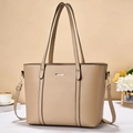 Detailed close-up of a large beige tote bag with a golden metal piece in home setting - Khaki