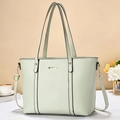 Close-up of mint green tote bag with decorative gold bar and detachable strap - Green