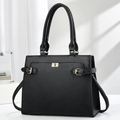 Close-up of black pebble leather tote bag with golden twist lock and textured finish - Black