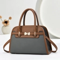 Détail du sac à main en cuir grainé avec nœud doré métallique et couleurs contrastées - Gris