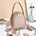 Detail of beige quilted leather handbag featuring dual gold zippers and woven shoulder strap - Khaki