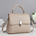 Detalle de bolso de mano beige en cuero granulado con hebilla plateada y asa redonda - Caqui