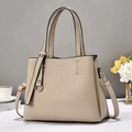 Détail du sac à main beige grainé avec finitions dorées sur une surface blanche - Khaki