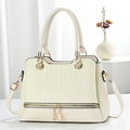 Beige strukturierte Handtasche mit Prägemuster und goldener Hardware auf weißem Grund - Cremeweiß