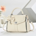 Chic beige crossbody bag with large bow and pearl chain charm on geometric display - White