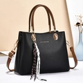 Black pebbled leather tote bag with brown handles and a stylish striped tassel charm - Black
