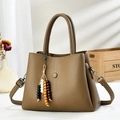 Khaki pebbled leather handbag with wide strap and beaded tassel on wood background - Dark Khaki