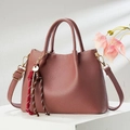 Detailed shot of pink pebble leather handbag featuring gold hardware and a tassel charm - Pink